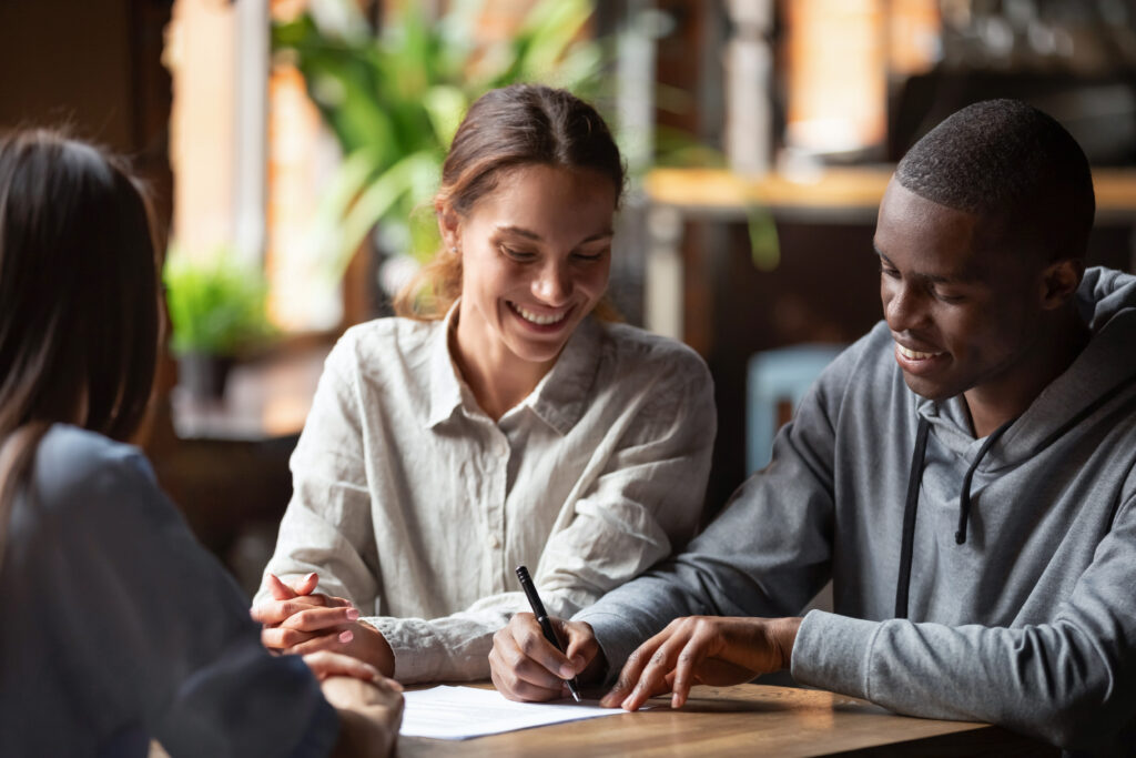 couple signing a contract with agent at desk