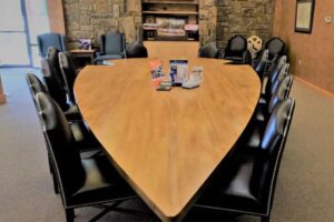 A large table shaped like an arrowhead surrounded by black chairs