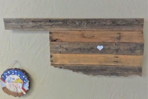 A wooden carving in the shape of Oklahoma, with a white heart painted in the middle