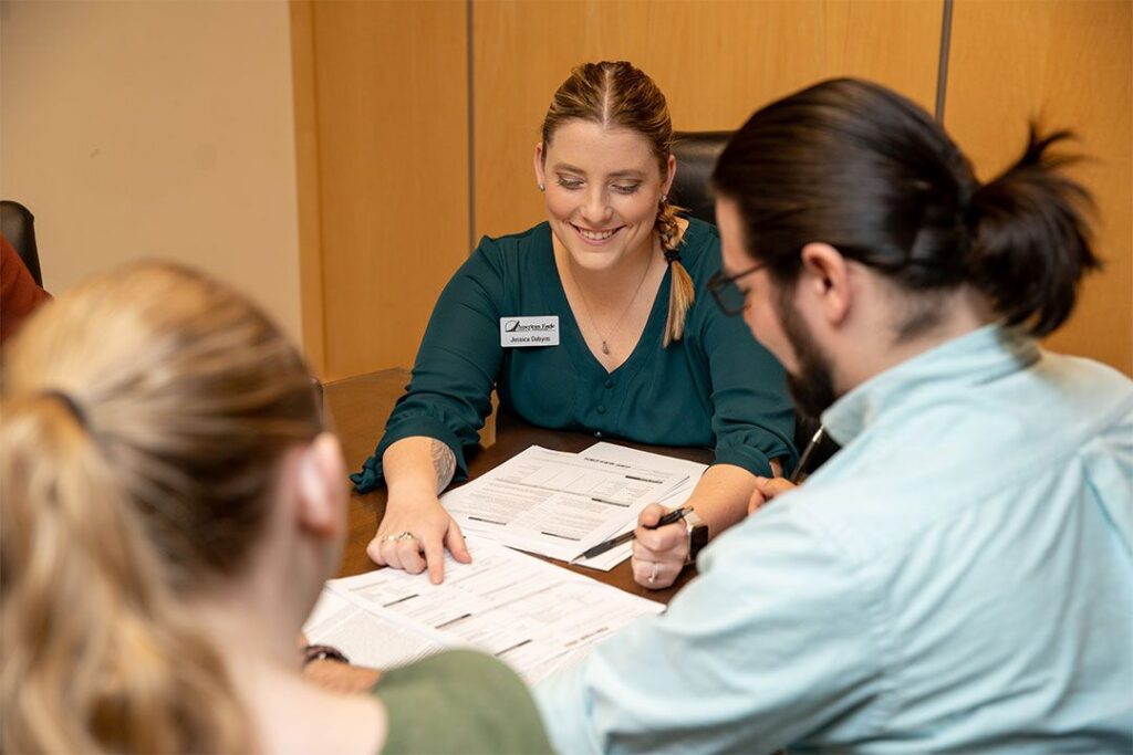 A woman points at a paper in front of 2 other people